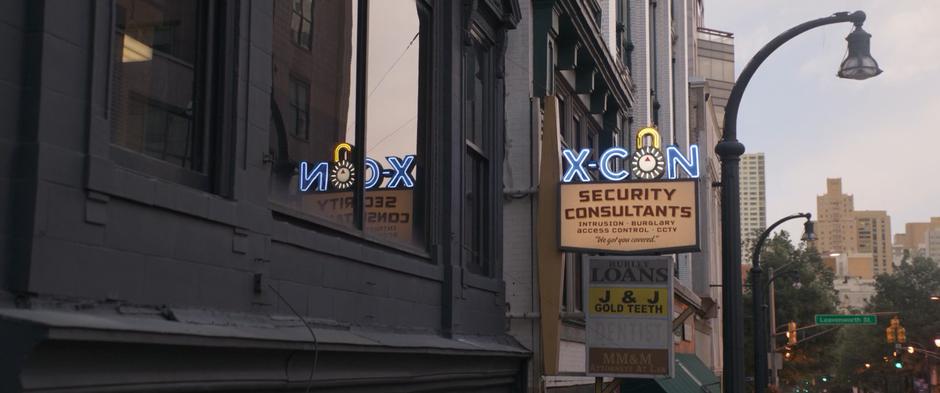 Establishing shot of the X-Con sign outside the second floor office.
