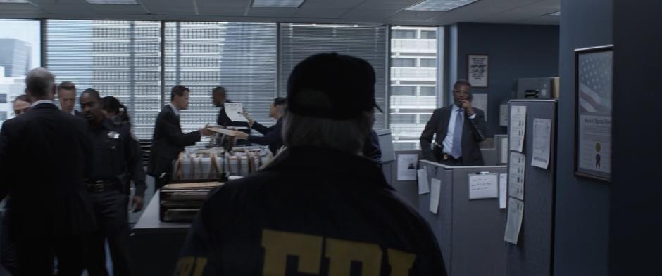 Hank walks out through the FBI offices disguised as an agent.