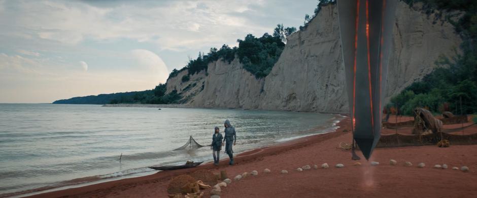 Michael and Saru walk along the beach past the Ba'ul obelisk.