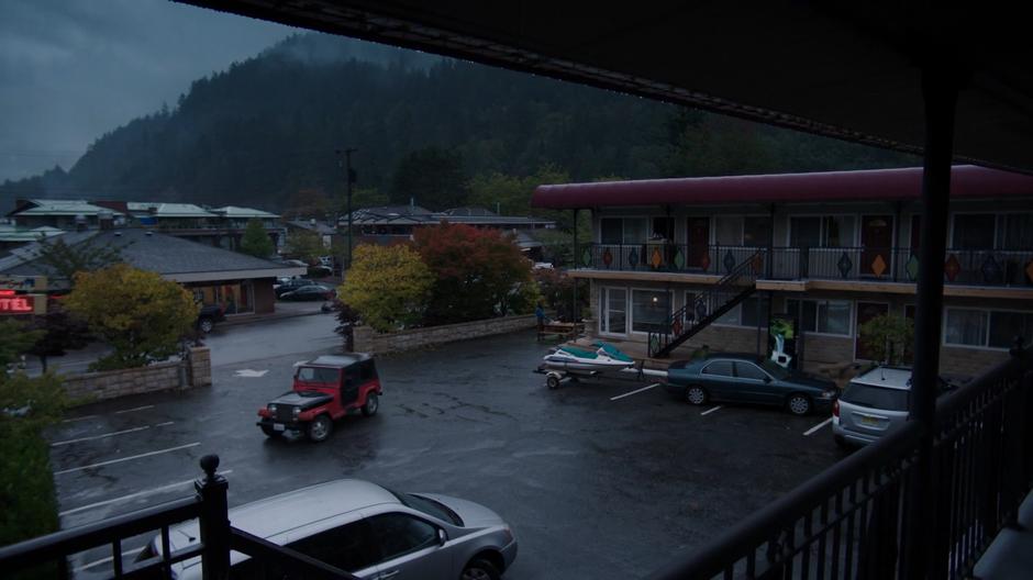 Maddie drives her jeep into the parking lot of the motel.