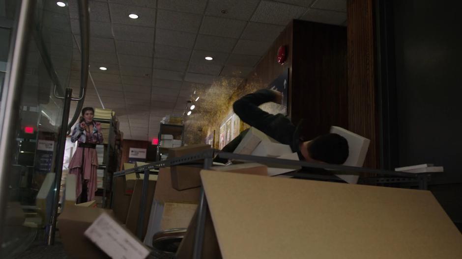 Chloe throws Zack back against a shelf in the archives with her powers.