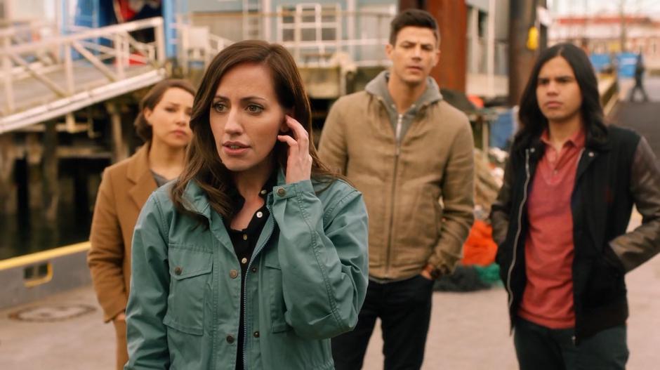 Nora, Barry, and Cisco watch as Dr. Tanya Lamden walks to King Shark on her earpieces.