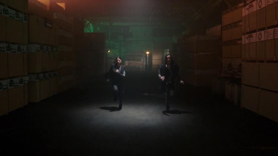 Fake versions of Mel and Jada run through the warehouse towards the Finches.