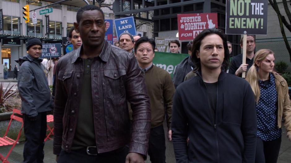 J'onn and Brainy walk at the front of the pro-alien protest.