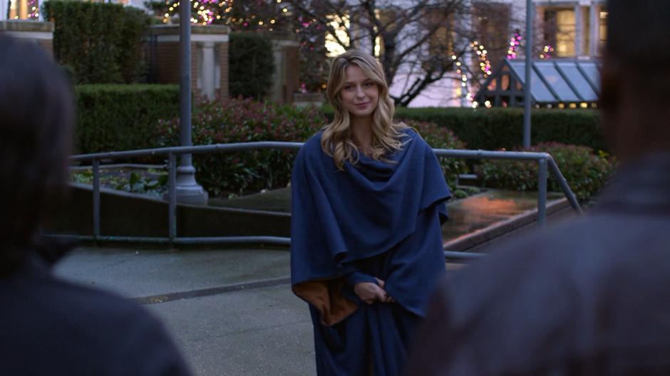 Kara walks up to Brainy and J'onn as she joins the protest in her traditional Kryptonian garb.