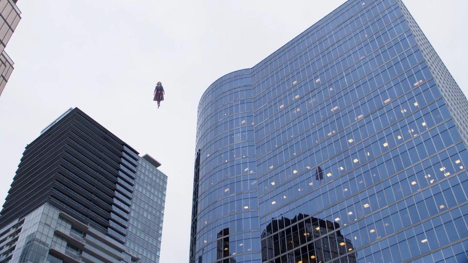 Kara flies in the air and watches over the protest for trouble.