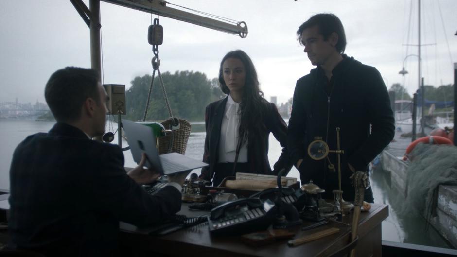 Harold the Herald holds up the laptop with a photo of the elixer to Julia and Quentin.
