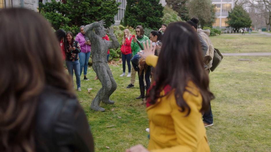 Maggie tries to freeze time using Mel's powers while students mingle around the frozen student.