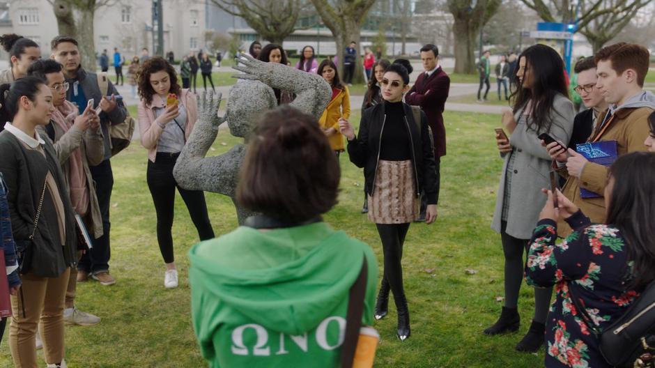 Harry and the sisters watch from the distance while a group of students stand around the frozen student assuming it is art.