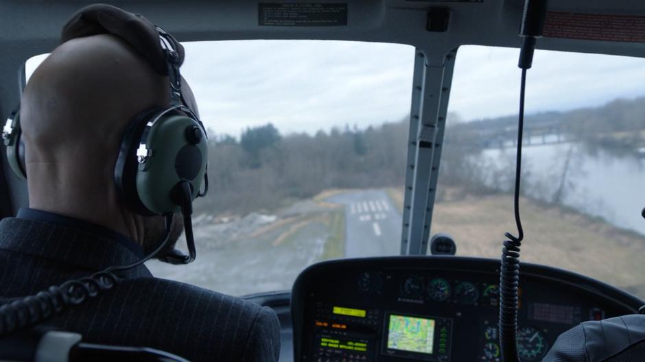 Lex sits in the front of the helicopter as it takes off and flies over the river.