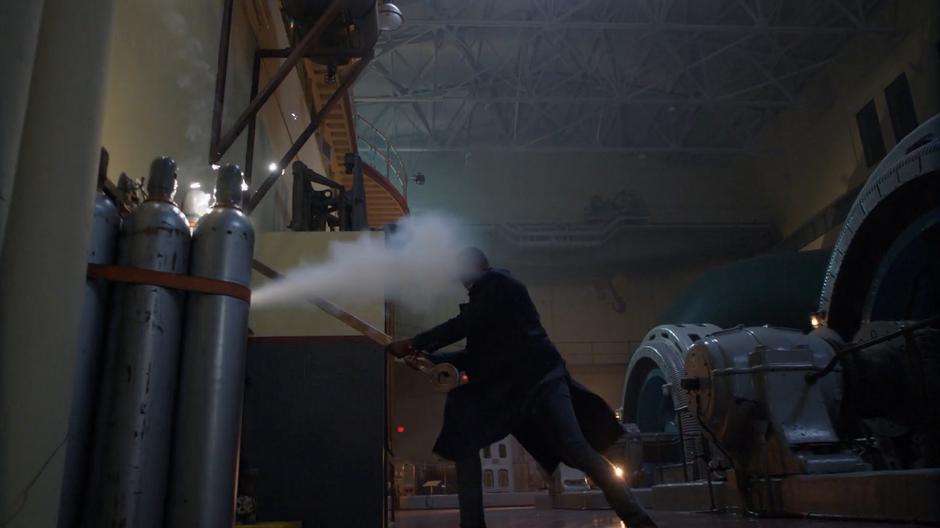 J'onn's swing misses Manchester when he disappears and he hits gas bottle releasing a plume.