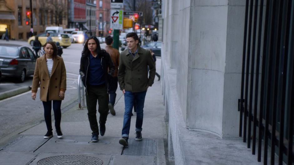 Nora, Cisco, and Barry walk up the sidewalk to the bank from the cold case file.