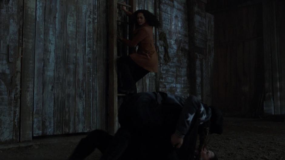 Macy climbs up a ladder while glancing over at Maggie who is attacking Mel.