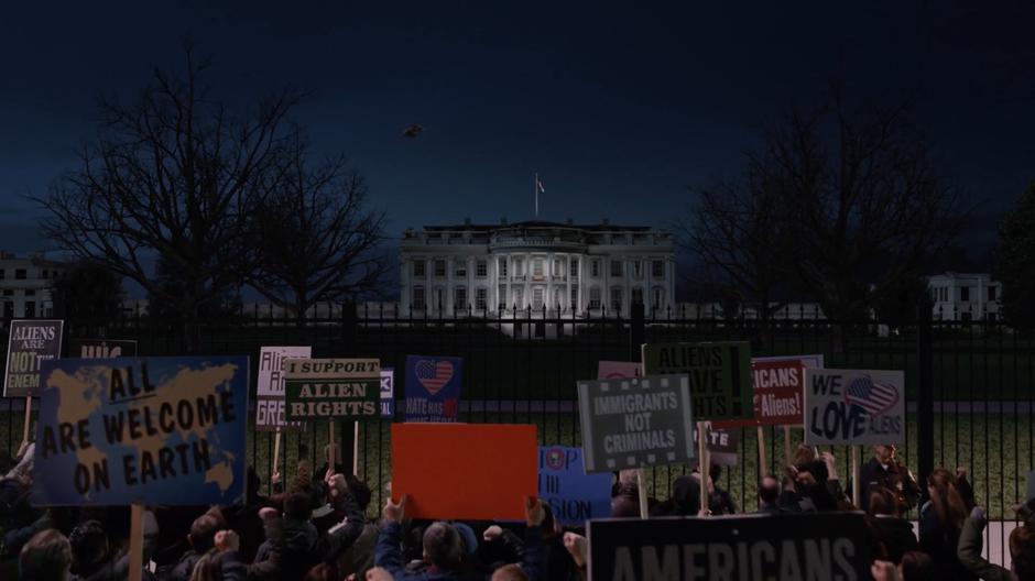 Kara flies overhead while people protest in front of the White House.