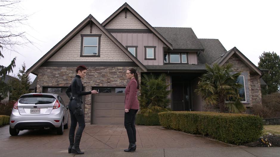 Alex presses the watch to summon Supergirl while standing outside the house with Lena.