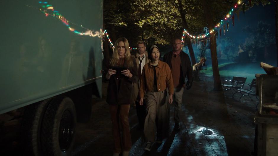 Sara leads Mona, Constantine, and Mick through the street at night.