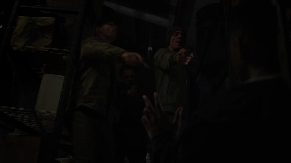 Three gang members point their guns at Tyrone as the shelf falls down onto them.