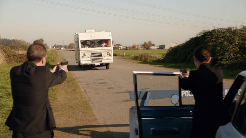 Several Time Bureau agents hold their guns at the RV as Ray drives it to a stop.