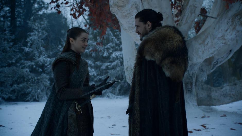 Arya holds Jon's sword and comments on its weight to him.