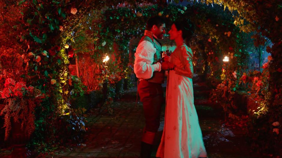 Sanjay and Zari stand in an arched pathway of flowers as the dance begins.