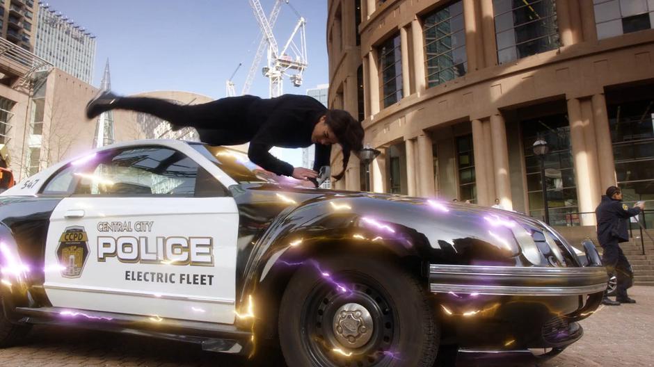 Nora flies over a parked police car which sparks with her electricity.