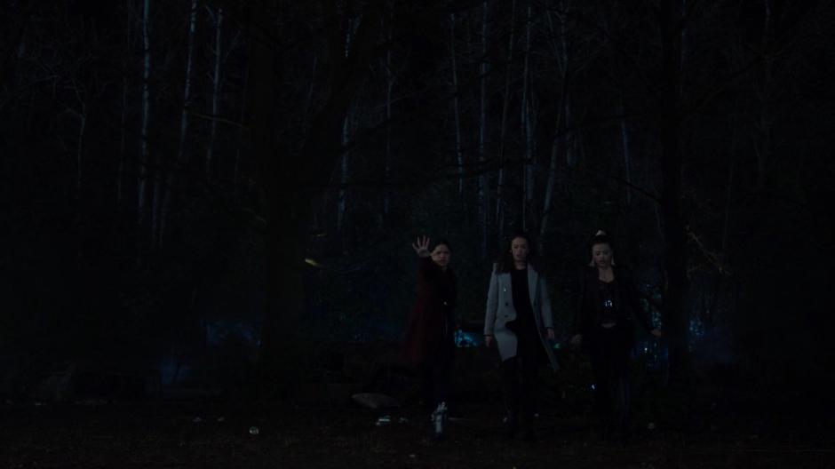 Mel holds out her hand to freeze the demon while Tessa and Maggie wait for Macy to run over to them.