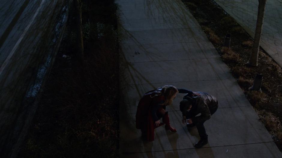 Kara lands down the street with the man from the crash after flying away from the three idiots.
