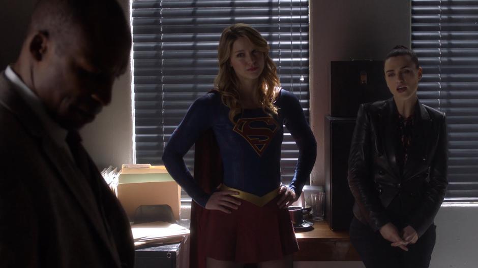 Lena explains to the warden the evidence she has on him while Kara stands with her hands on her hips.