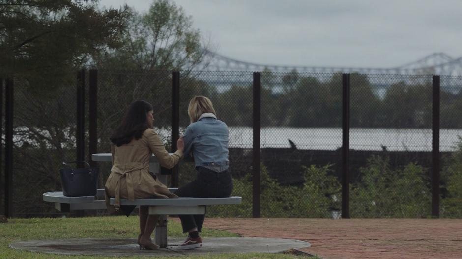 Lia Dewan puts a supportive hand on Tandy's shoulder as they talk at a picnic table after Tyrone has left.