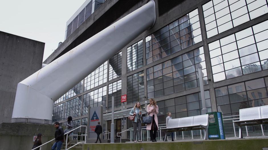 Edna and Kara walk to a bench in front of the building.