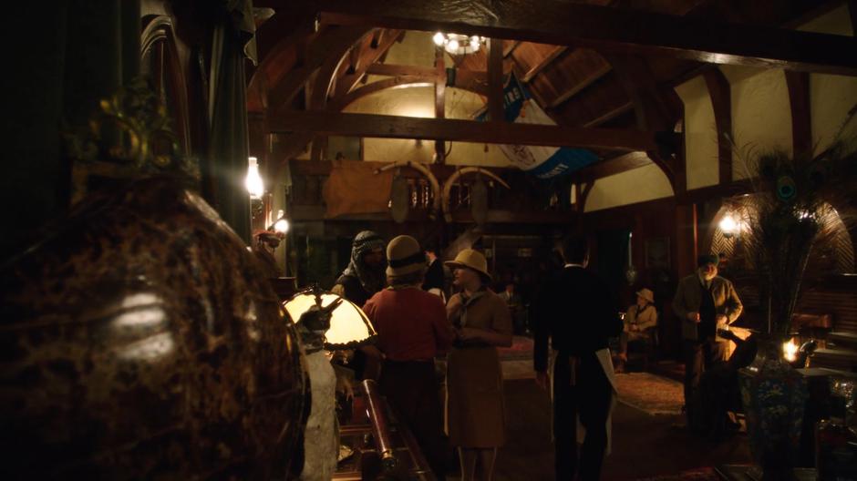 People mill around inside the main room of the Adventurers' Society.