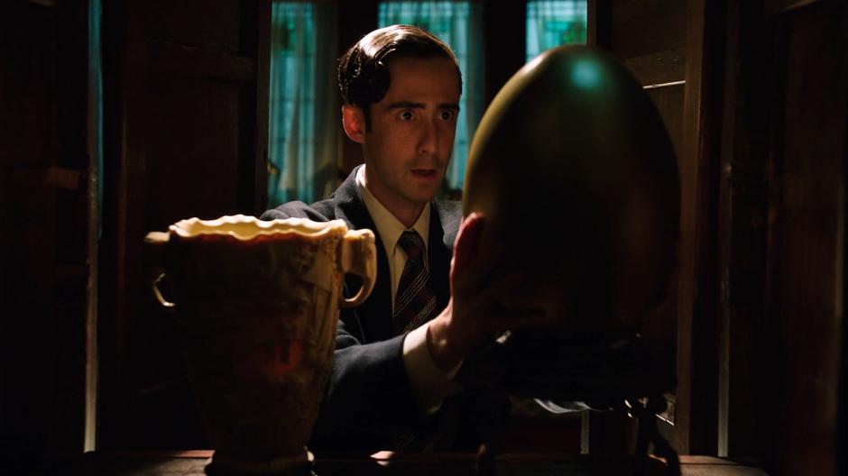 Gordon Gilchrist's assistant Vincent takes the real golden egg from the cabinet where he hid it.