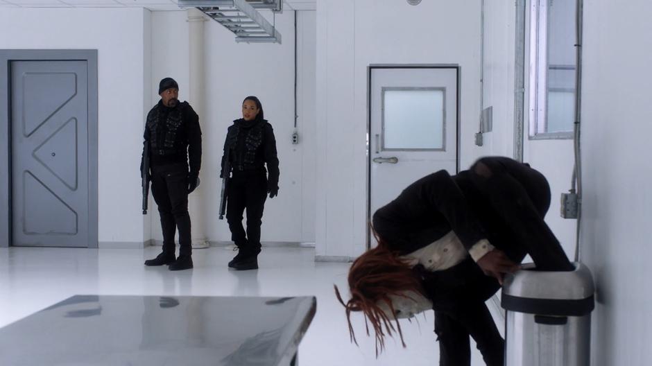 Joe and Iris watch as Peter Merkel emerges from a trash can.