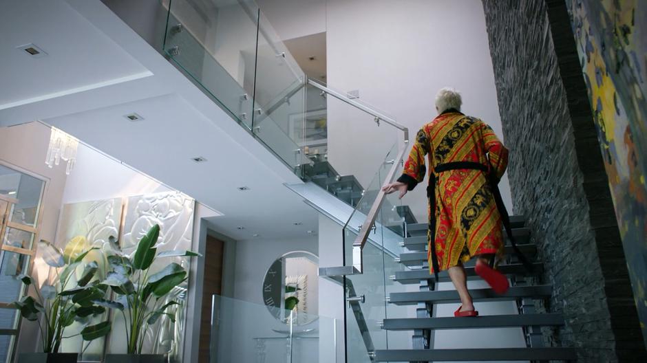 Blaine climbs the stairs to his bedroom wearing a colorfull robe and red slippers.