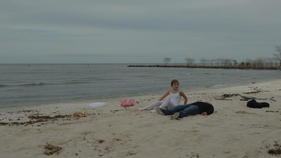 Young Tandy wakes up on the beach next to Tyrone and looks around.