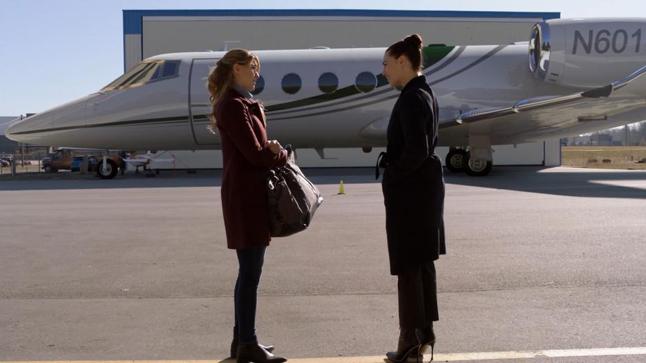 Lena convinces Kara that they should travel together while standing in front of her fancy plane.