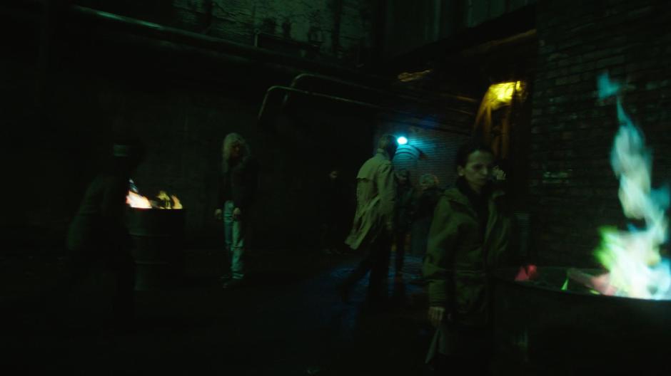 Constantine walks down a darkened alley past demons.