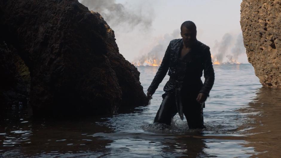 Euron emerges from the water as his fleet burns in the bay behind him.