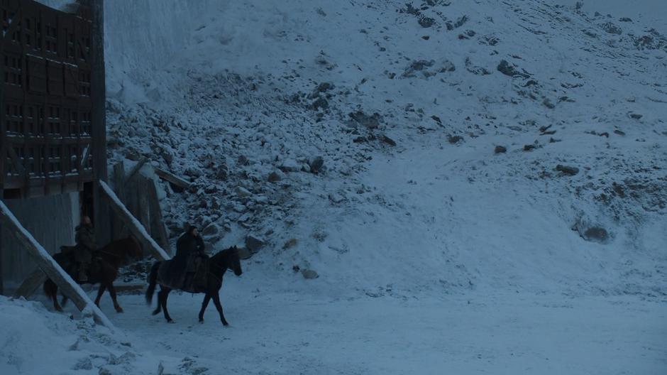 Tormund Giantsbane and Jon ride out through the gate north of The Wall.