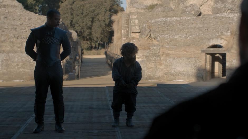 Tyrion stands chained and puts his head down when Grey Worm commands him to stop talking.