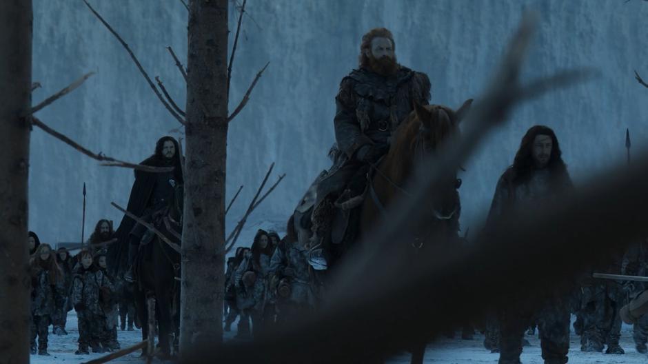 Jon and Tormund Giantsbane ride at the front of a large group of Wildlings heading into the forest.