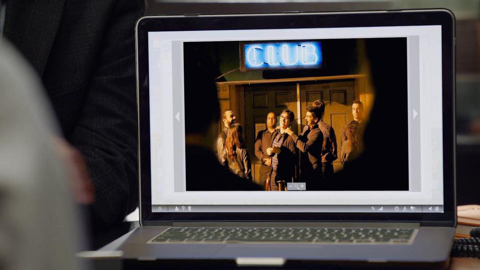 A photograph of Graham Moss hanging out with other zombies outside a club is shown on the principal's laptop.