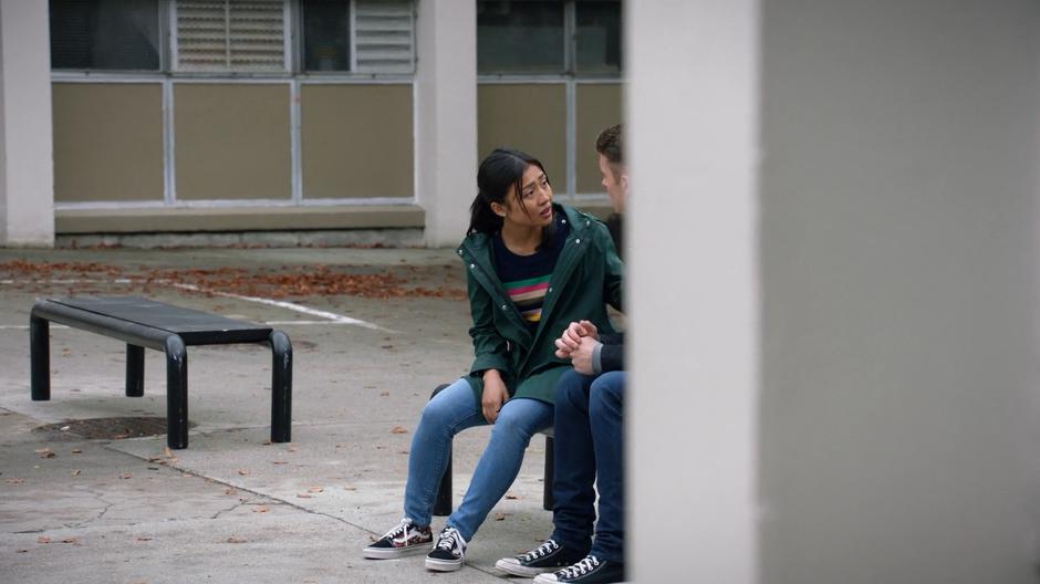 Amy sits on a bench talking to her ex-boyfriend Jamie in the yard behind the school.