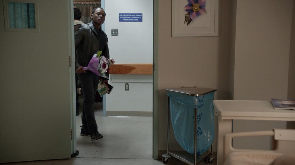 Clive approaches Michelle's hospital room with flowers and sudoku books.