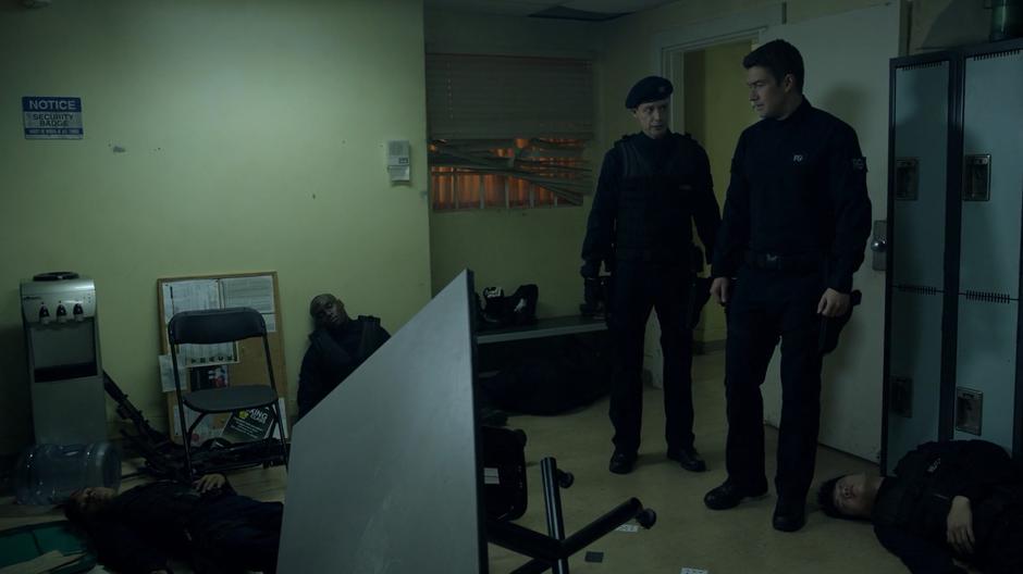 Hobbs and Major examine the break room which is filled with bodies.