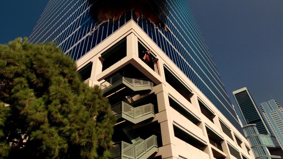 Kara flies away from the burning building after stabilizing the support columns.