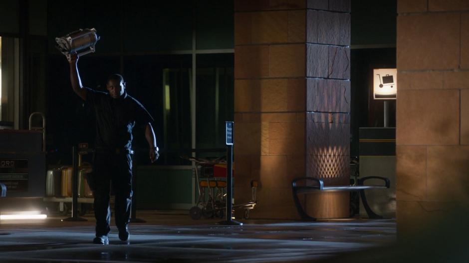 Hank holds up the disarmed bomb as he walks out of the building.