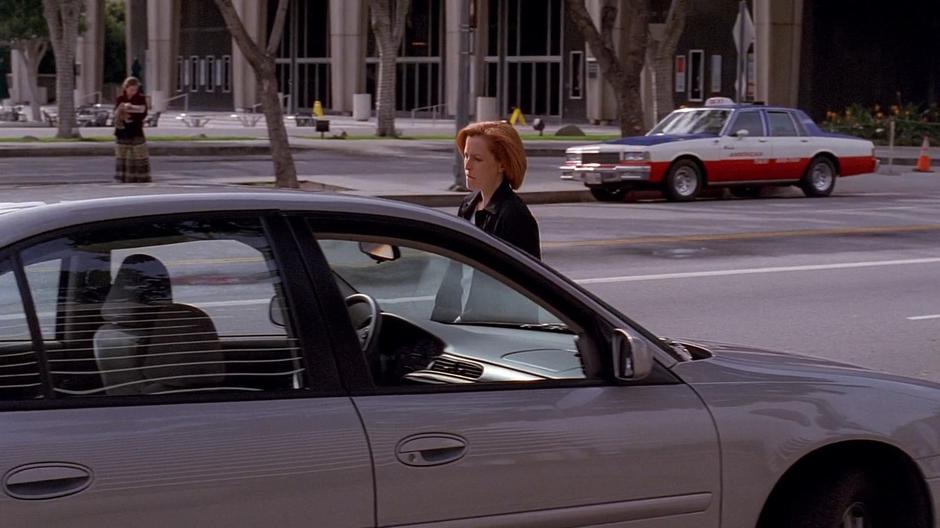 Scully walks around to the driver's side of her car.