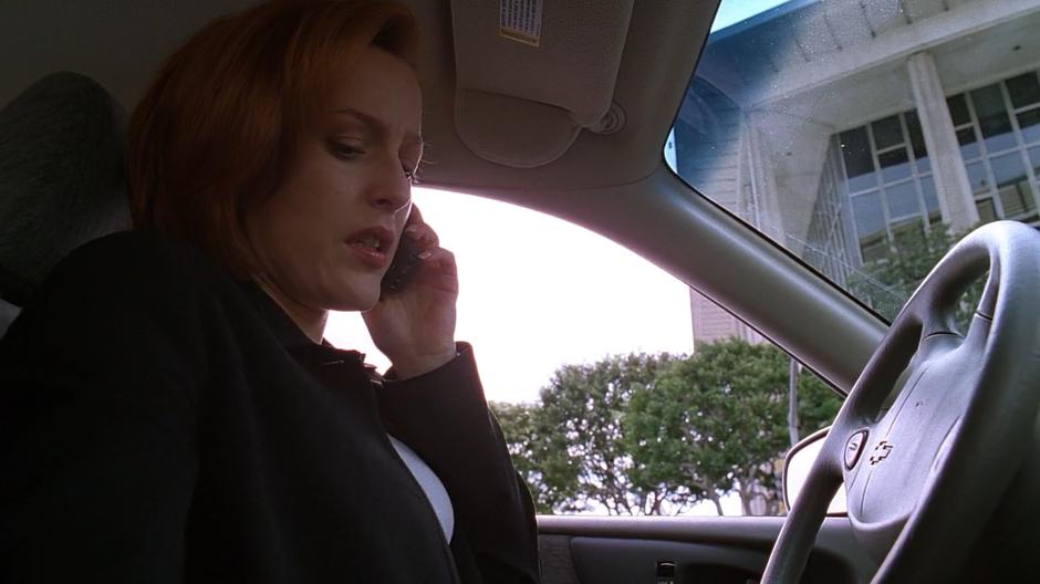 Scully answers a call from Mulder after getting into her car.