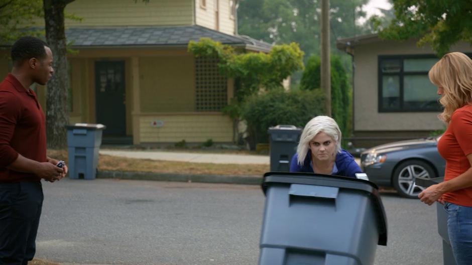 Clive and Mrs. Jones watch as Liv runs up the driveway pushing one of the trash cans with a determined look.